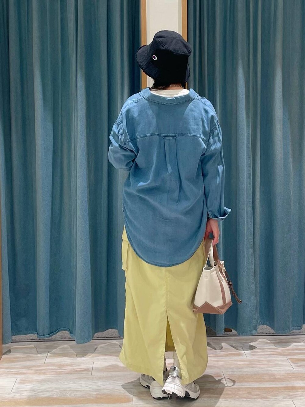 ブルー系のシャツ/ブラウス、ブラウン系のトートバッグ、ホワイト系のスニーカーを着用したレディースの春コーディネートの3枚目の写真