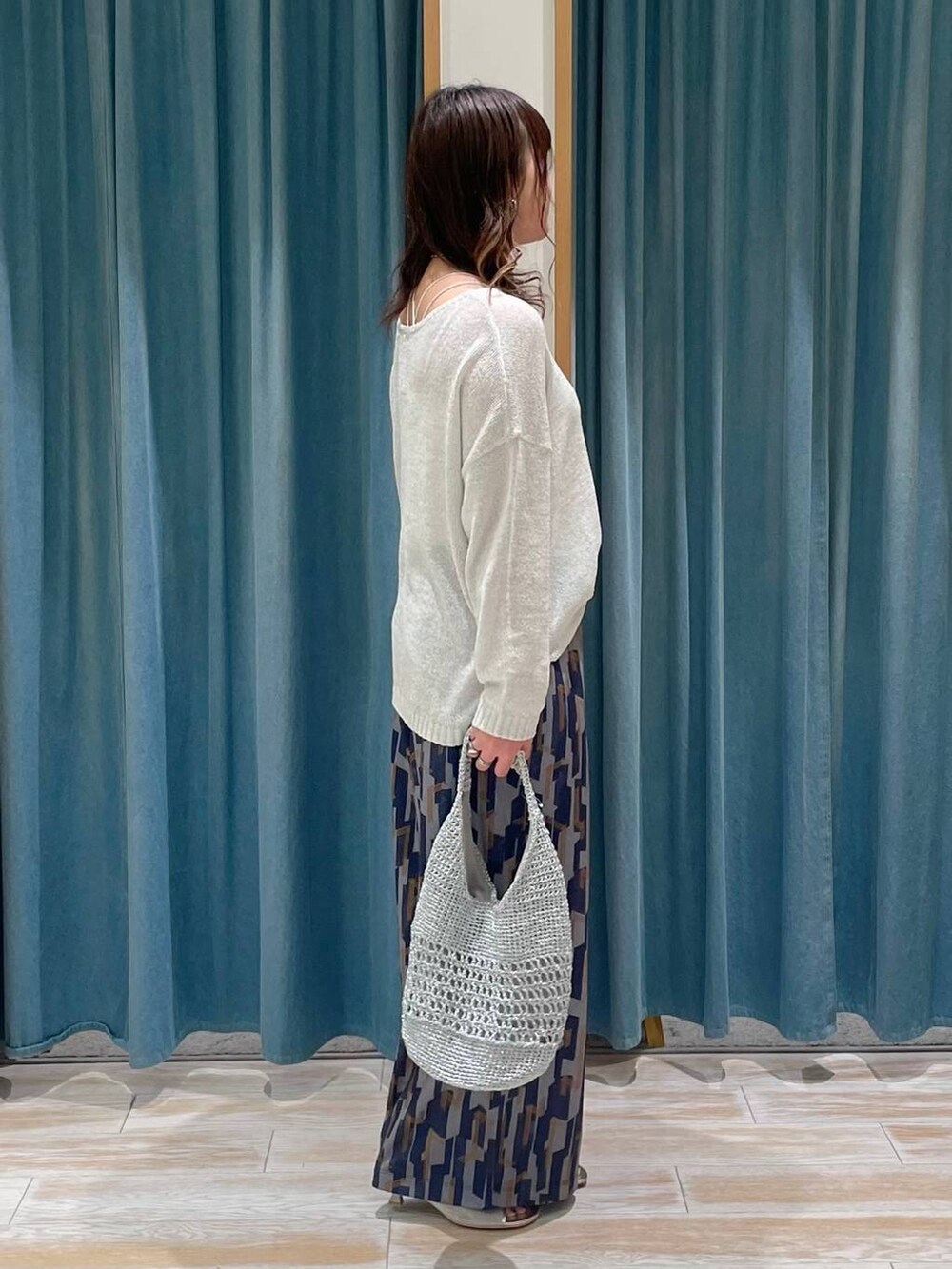 シルバー系のサンダル、グレー系のハンドバッグ、ホワイト系のニット/セーターを着用したレディースの春コーディネートの2枚目の写真