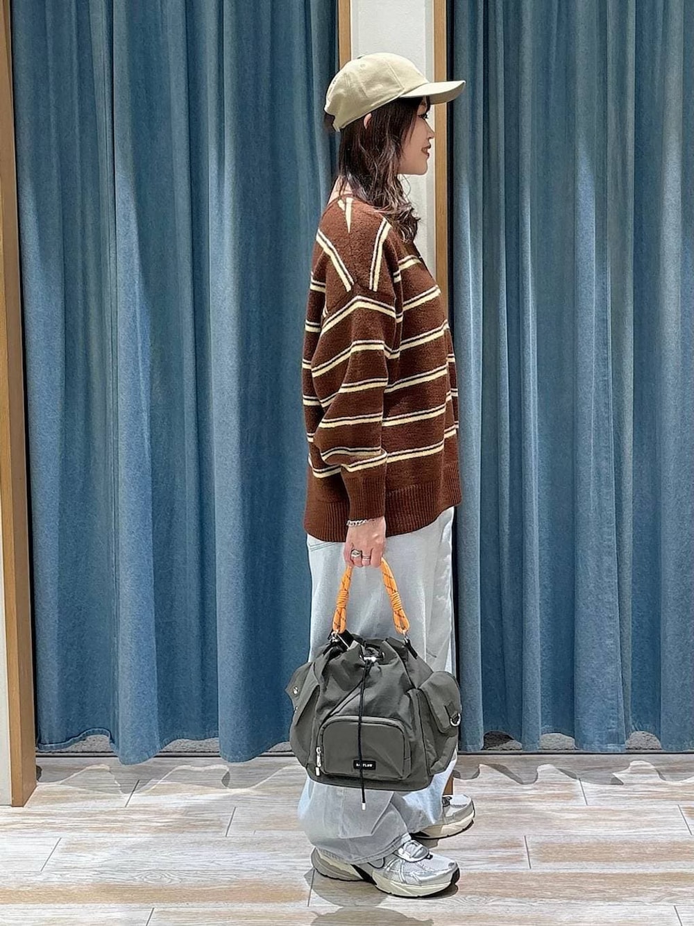 グリーン系のハンドバッグ、ブルー系のデニムパンツ、ブラウン系のニット/セーターを着用したレディースの冬コーディネートの2枚目の写真