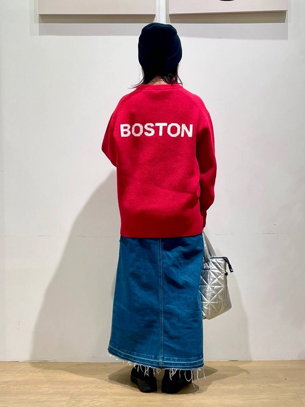 ブルー系のデニムスカート、レッド系のニット/セーター、ブラック系のブーツを着用したレディースの秋コーディネートの2枚目の写真