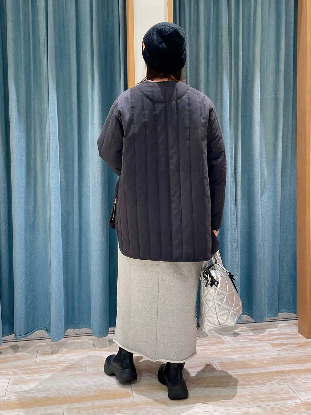 ピンク系のニット/セーター、シルバー系のトートバッグ、ブラック系のブーツを着用したレディースの冬コーディネートの2枚目の写真