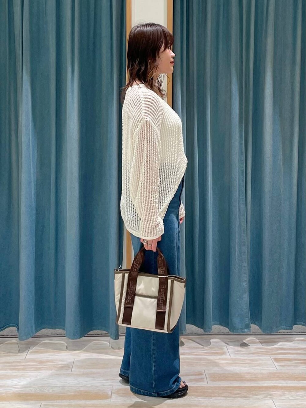 ホワイト系のキャミソール、ブルー系のデニムパンツ、ベージュ系のトートバッグを着用したレディースの春コーディネートの2枚目の写真