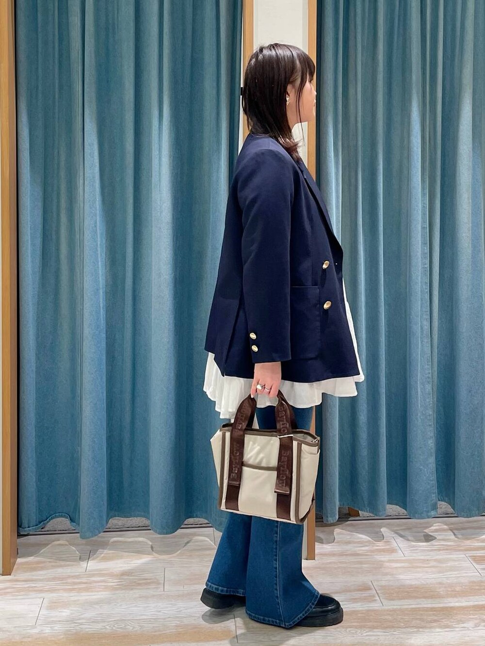 ブルー系のテーラードジャケット、ブルー系のデニムパンツ、ベージュ系のトートバッグを着用したレディースの春コーディネートの2枚目の写真