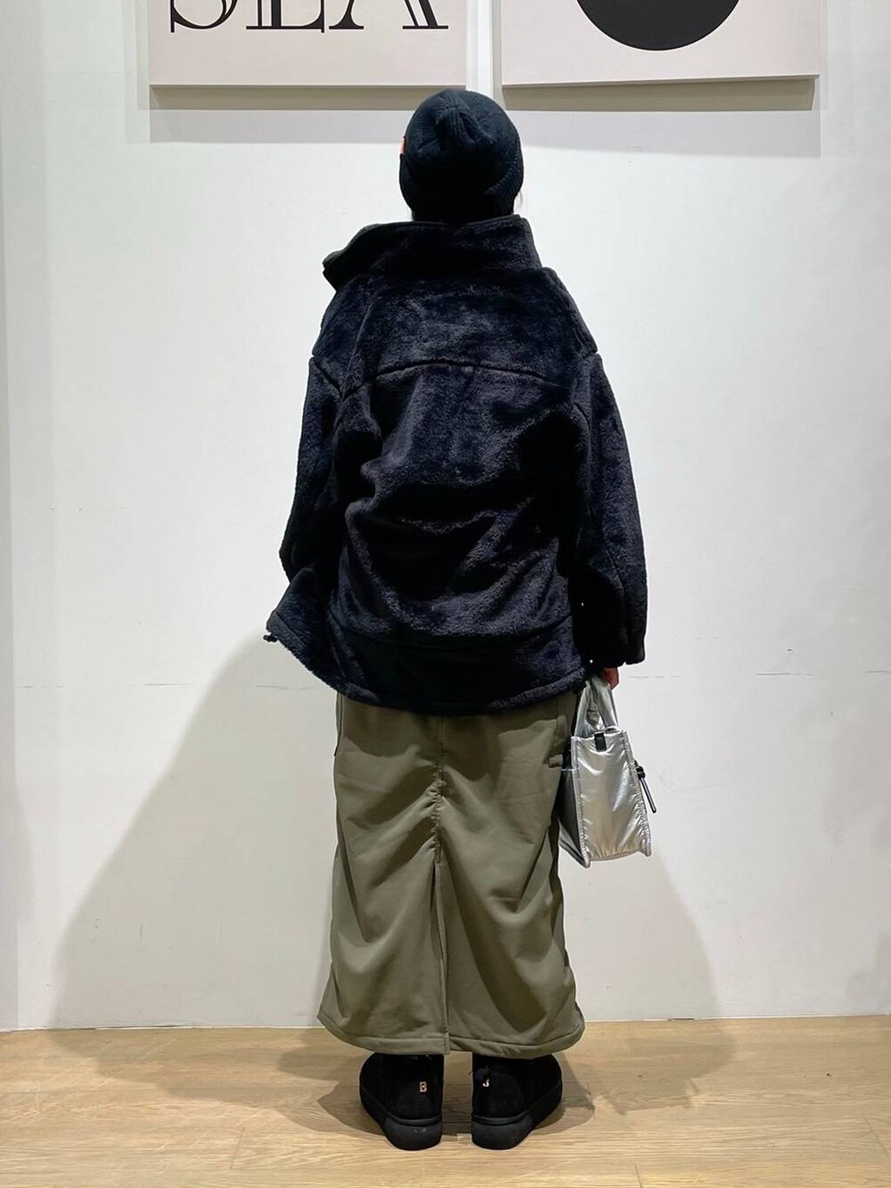 シルバー系のショルダーバッグ、ブラック系のブルゾン、グリーン系のスカートを着用したレディースの秋コーディネートの3枚目の写真