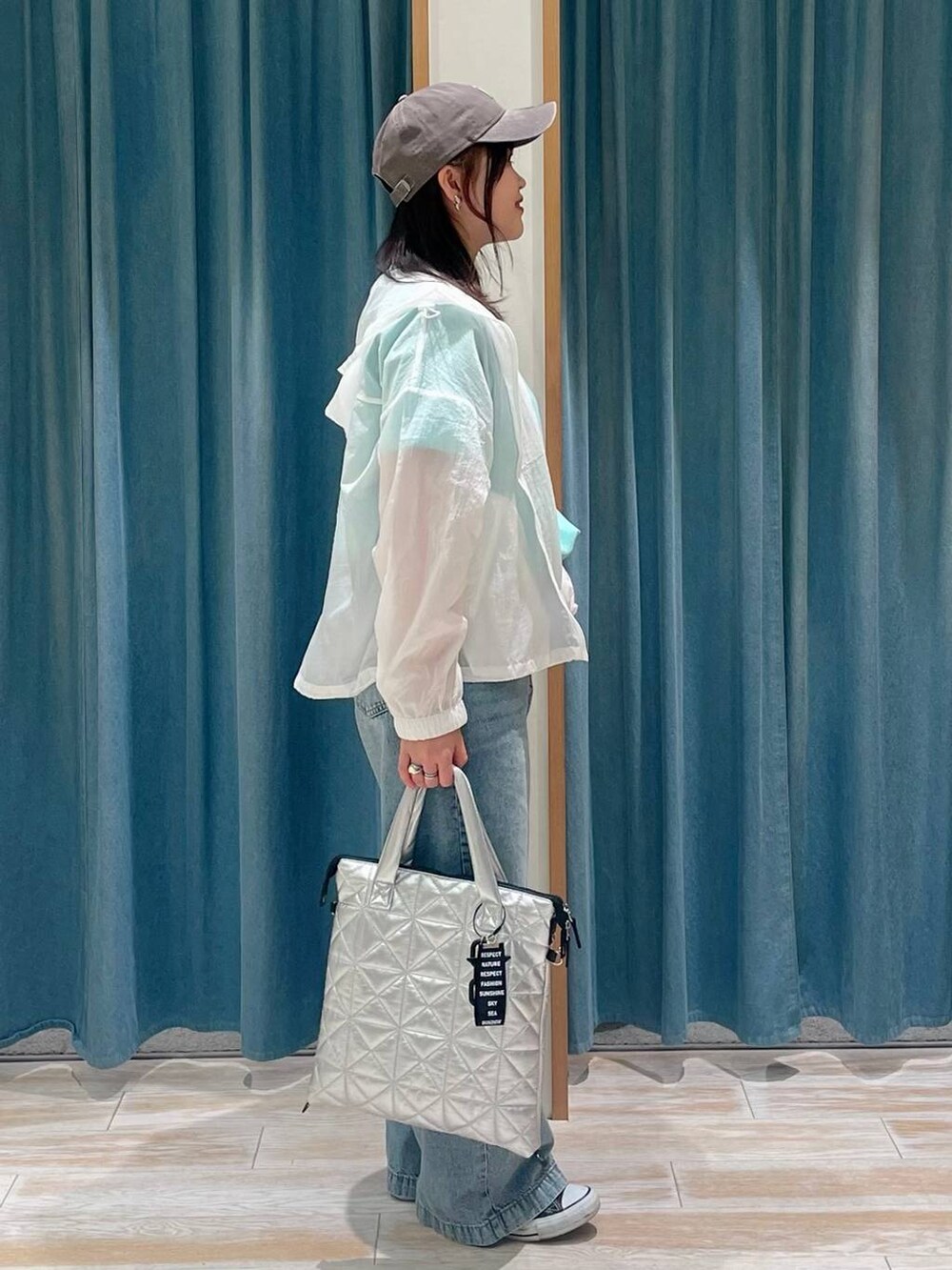 グリーン系のTシャツ/カットソー、ブルー系のデニムパンツ、シルバー系のトートバッグを着用したレディースの春コーディネートの2枚目の写真