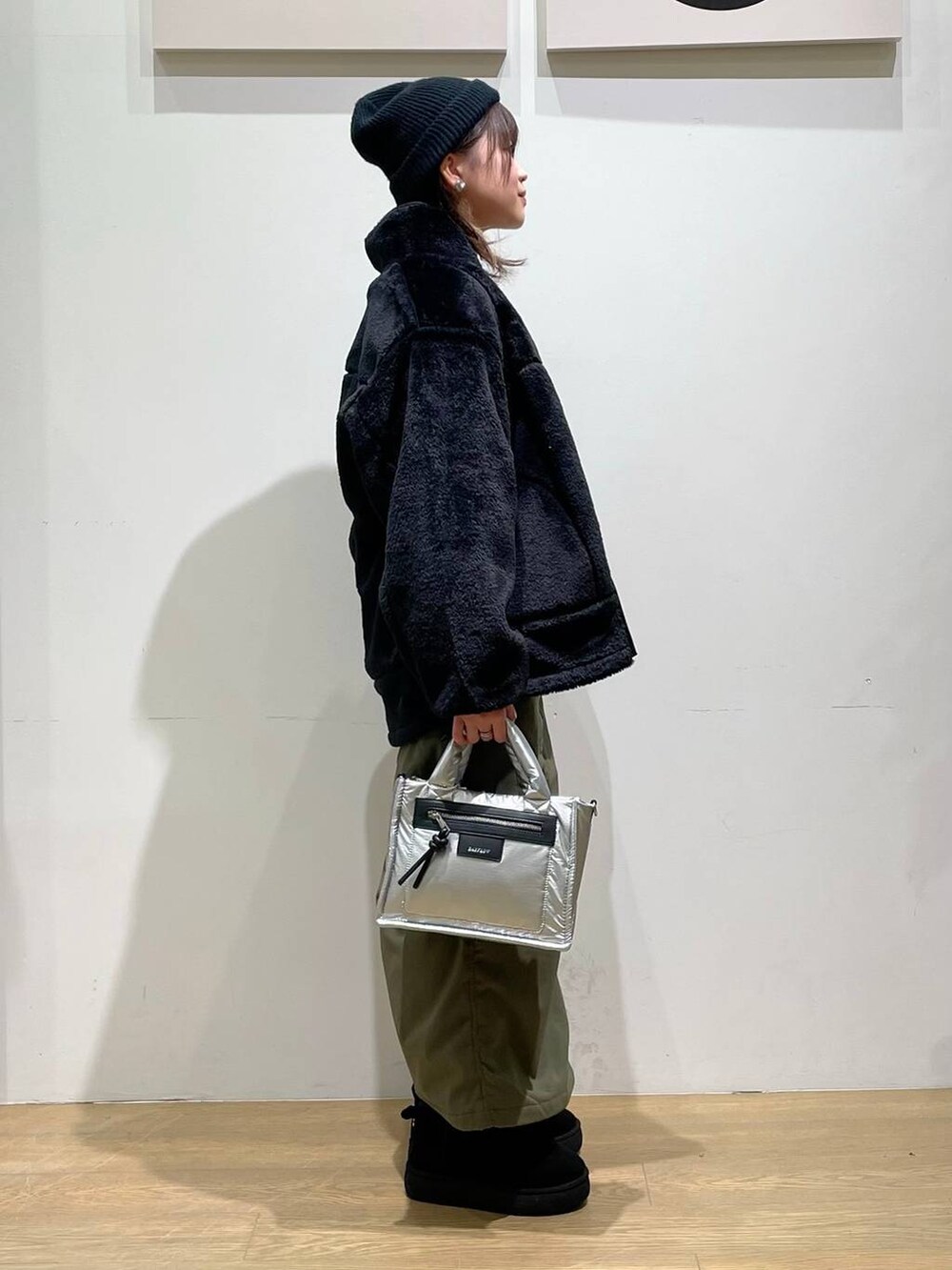 シルバー系のショルダーバッグ、ブラック系のブルゾン、グリーン系のスカートを着用したレディースの秋コーディネートの2枚目の写真