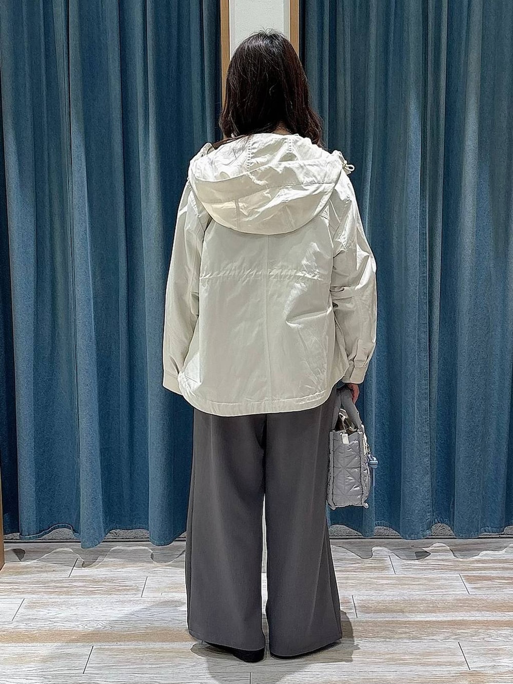 グレー系のショルダーバッグ、ホワイト系のマウンテンパーカー、ブラック系のバレエシューズを着用したレディースの春コーディネートの3枚目の写真