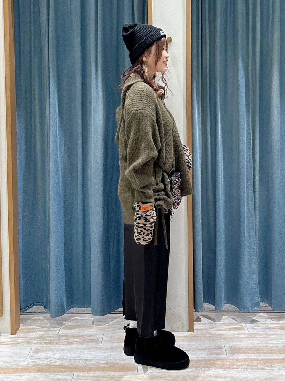 ブラウン系のショルダーバッグ、ブラック系のブーツ、ブラック系のスカートを着用したレディースの秋コーディネートの2枚目の写真