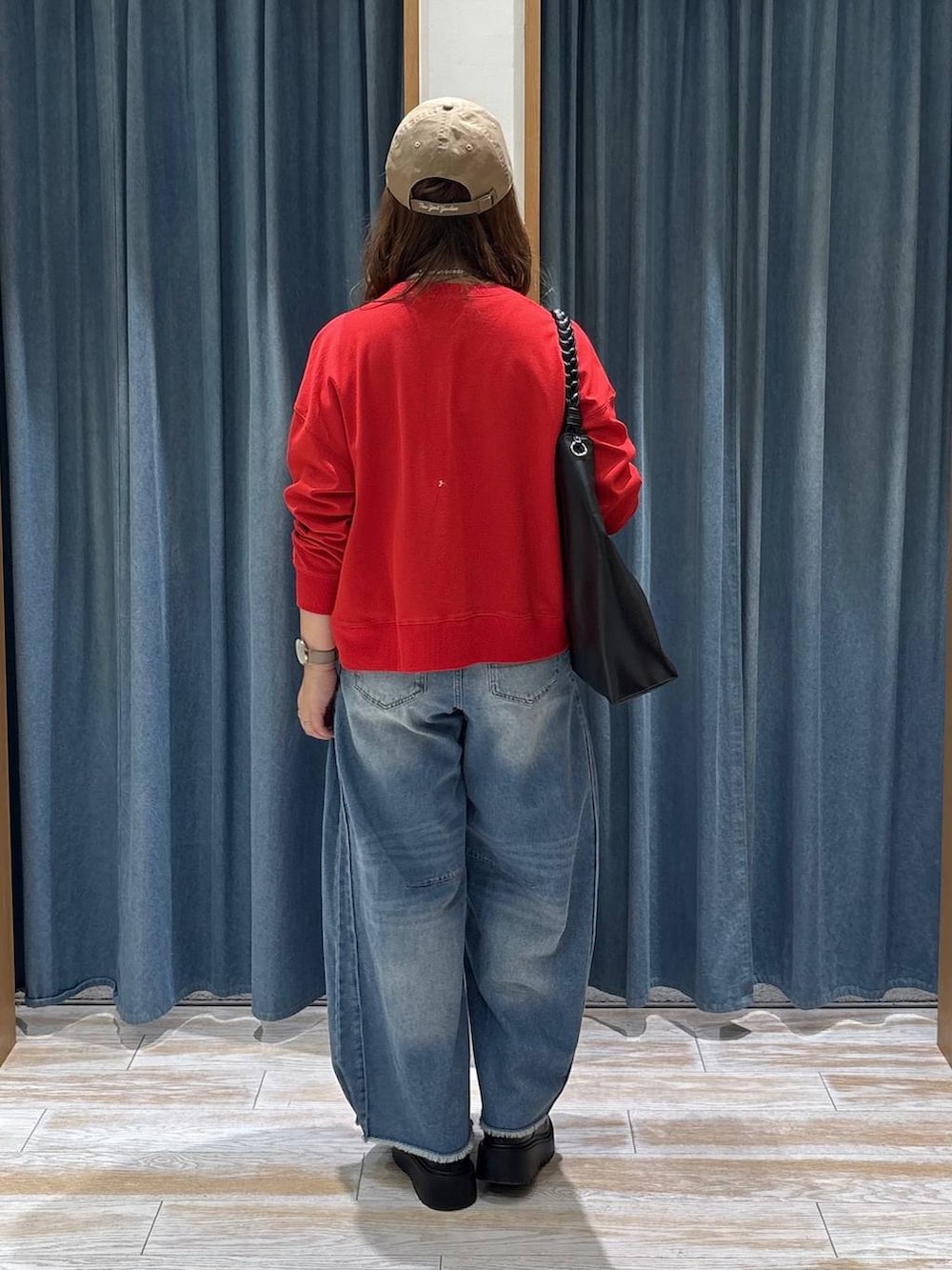 ブルー系のデニムパンツ、レッド系のカーディガン/ボレロ、ブラック系のブーツを着用したレディースの秋コーディネートの3枚目の写真