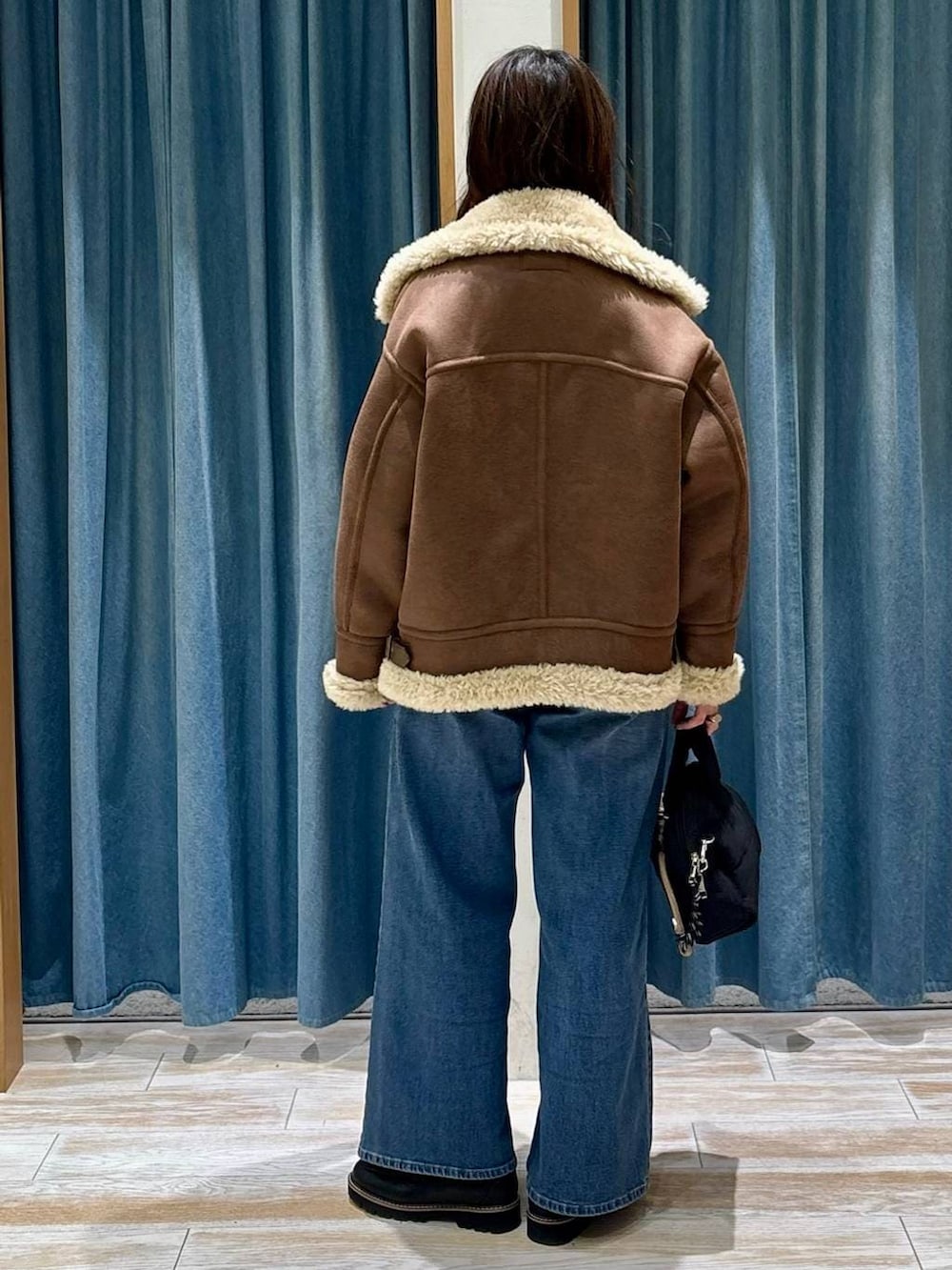 ブラック系のローファー、ブルー系のデニムパンツ、ブラック系のボストンバッグを着用したレディースの秋コーディネートの3枚目の写真