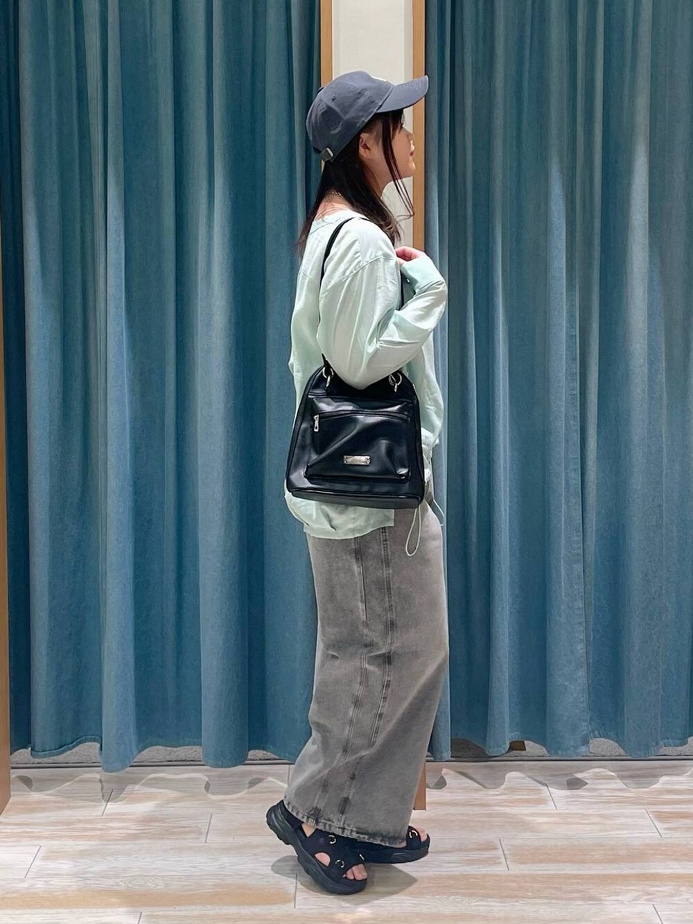 グレー系のデニムパンツ、グリーン系のシャツ/ブラウス、ブラック系のサンダルを着用したレディースの春コーディネートの2枚目の写真