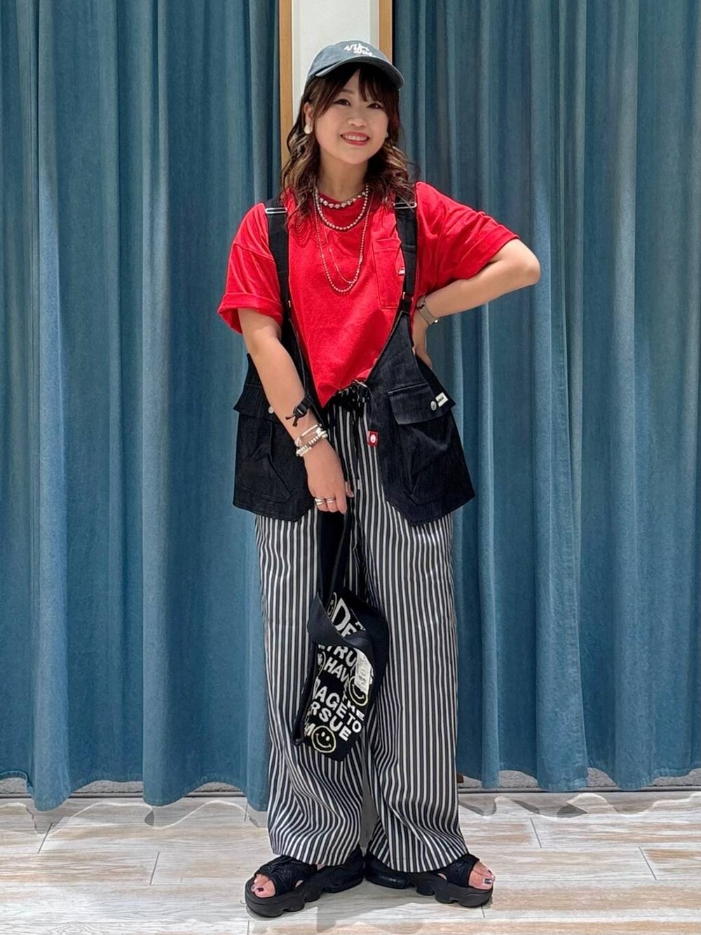 ブラック系のトートバッグ、レッド系のTシャツ/カットソー、その他のベストを着用したレディースの夏コーディネートの4枚目の写真