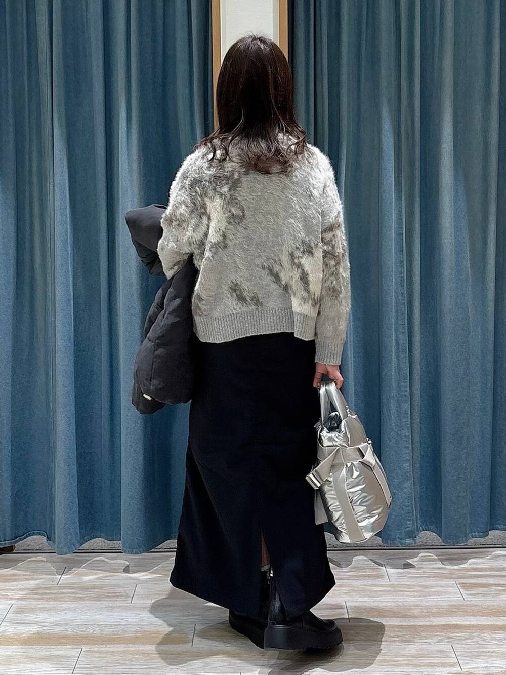 シルバー系のトートバッグ、ブラック系のブーツ、グレー系のダウンジャケット/コートを着用したレディースの冬コーディネートの3枚目の写真