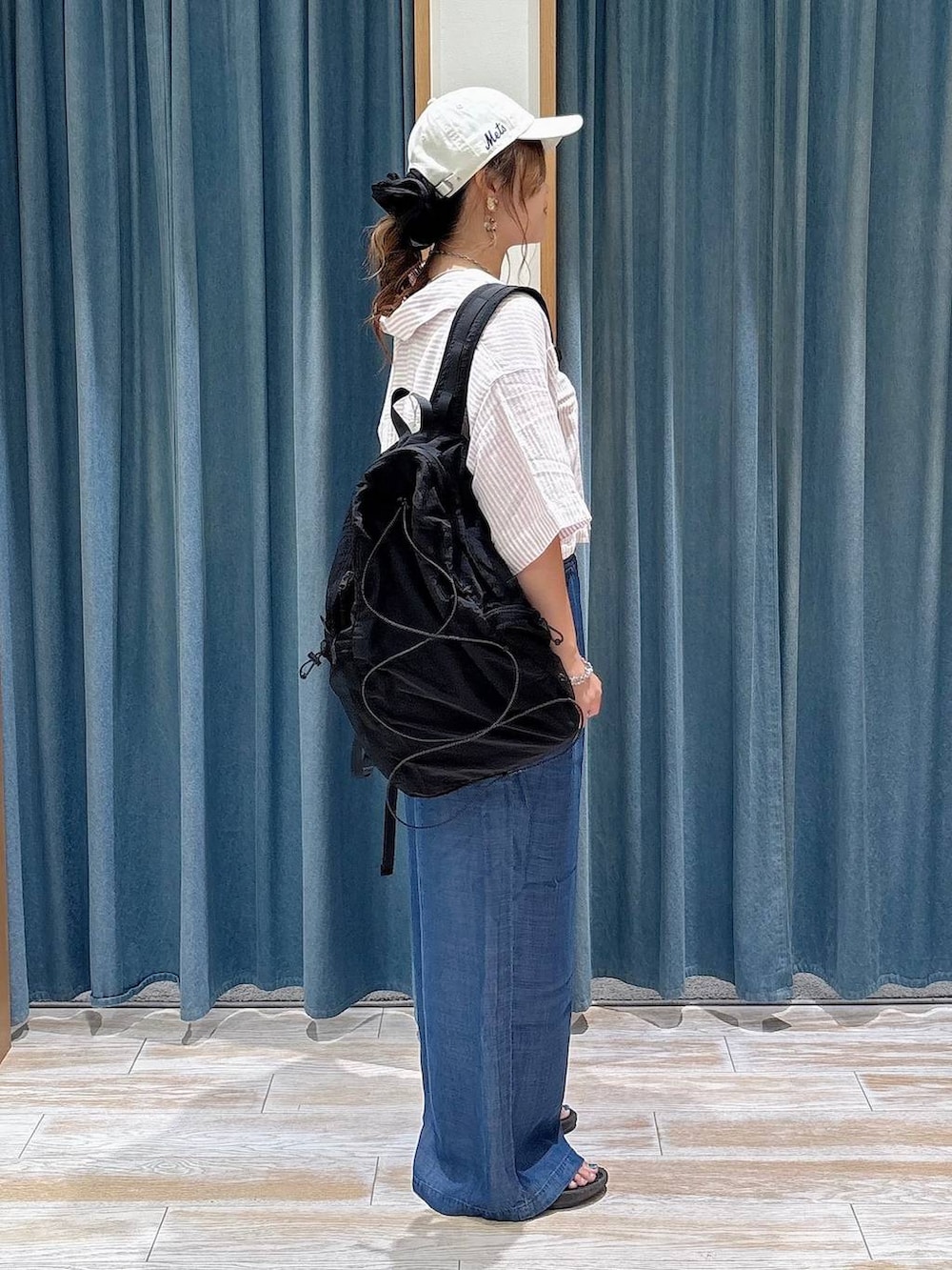ブラック系のバックパック/リュック、ブルー系のデニムパンツ、ブラック系のサンダルを着用したレディースの夏コーディネートの2枚目の写真