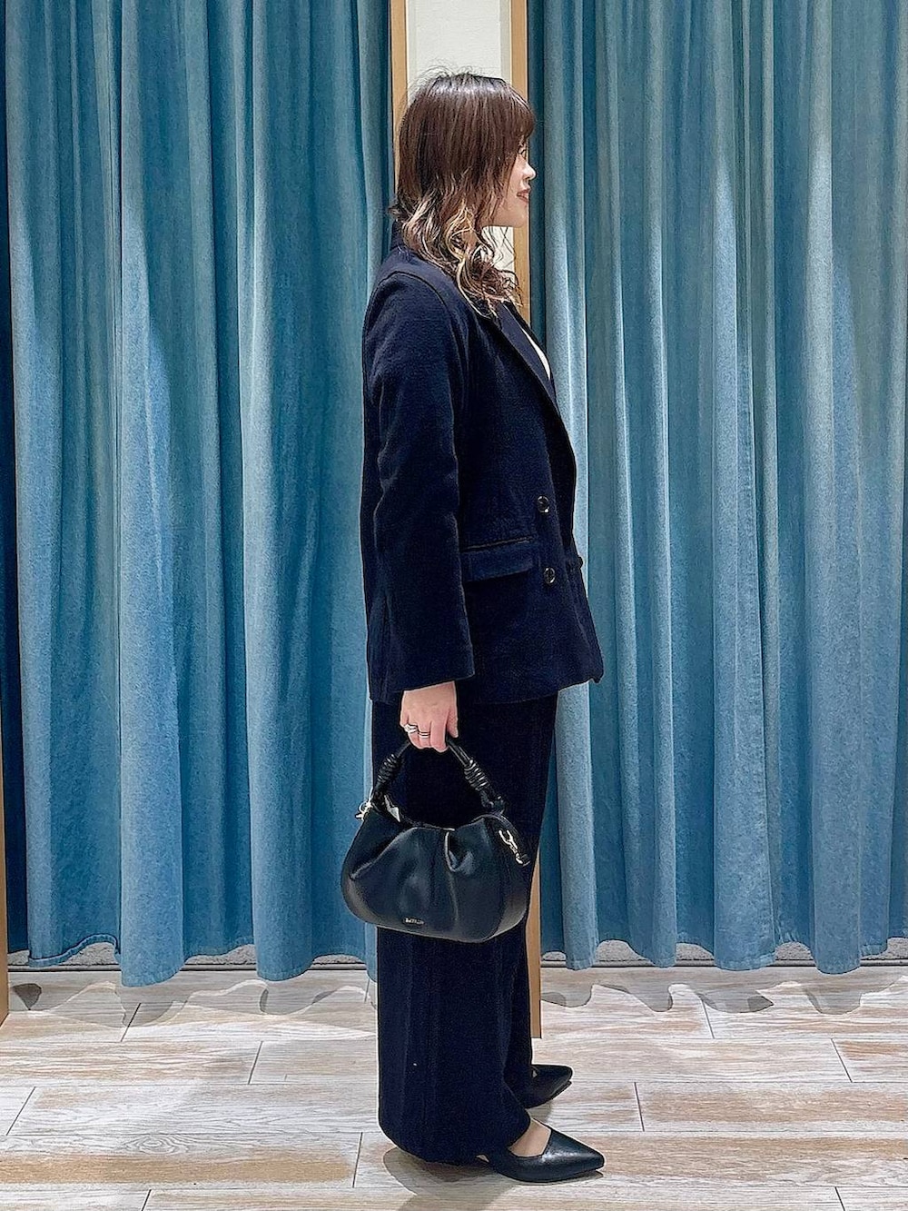 ブラック系のハンドバッグ、ブラック系のパンプス、ブラック系のテーラードジャケットを着用したレディースの春コーディネートの2枚目の写真