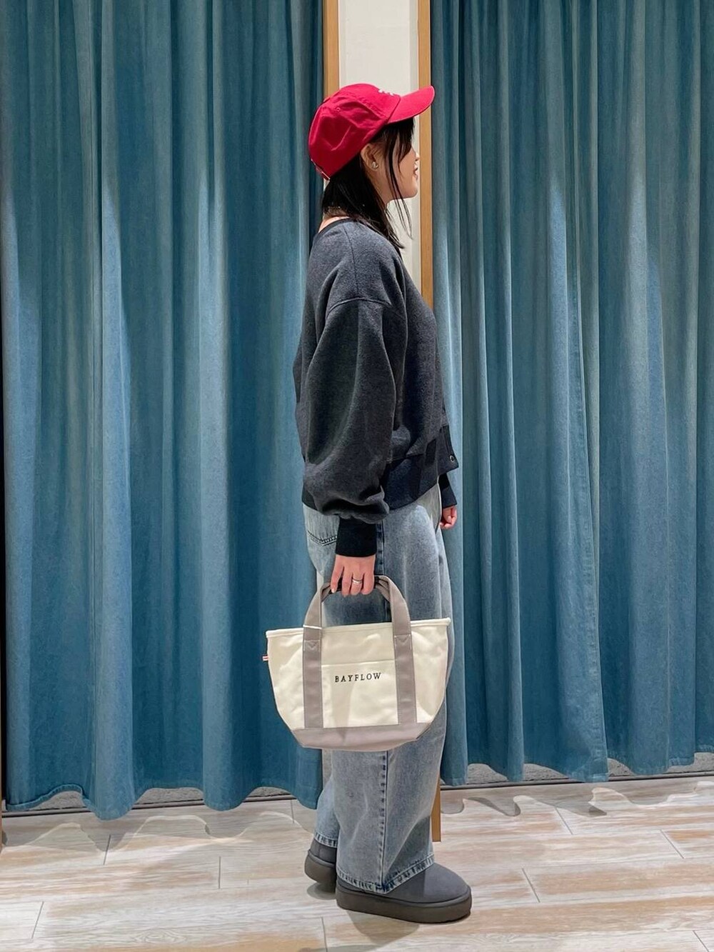 グレー系のブーツ、グレー系のトートバッグ、ブルー系のデニムパンツを着用したレディースの冬コーディネートの2枚目の写真