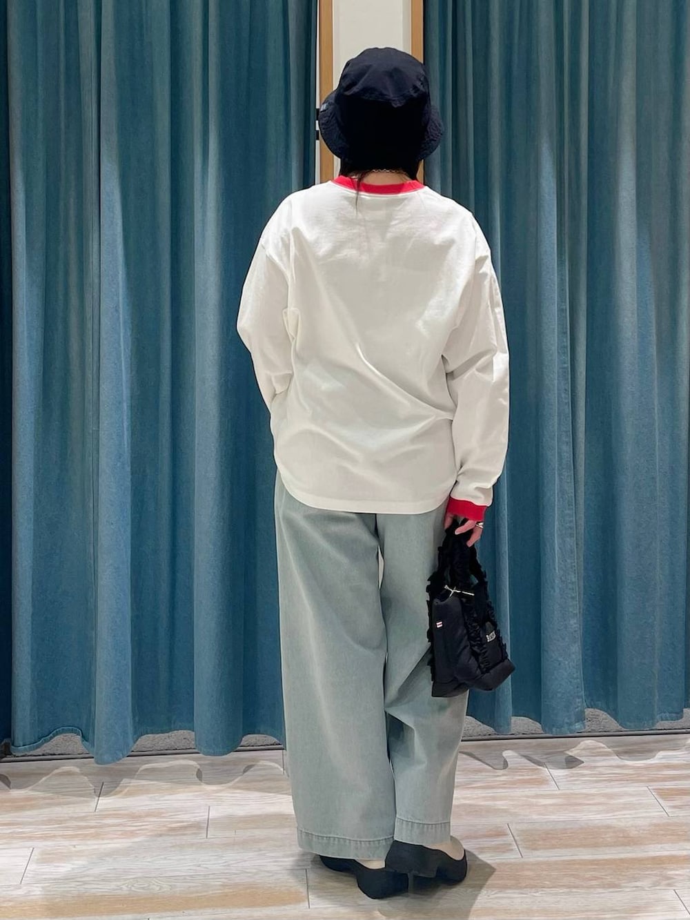 ホワイト系のブーツ、ブラック系のトートバッグ、グリーン系のデニムパンツを着用したレディースの冬コーディネートの3枚目の写真