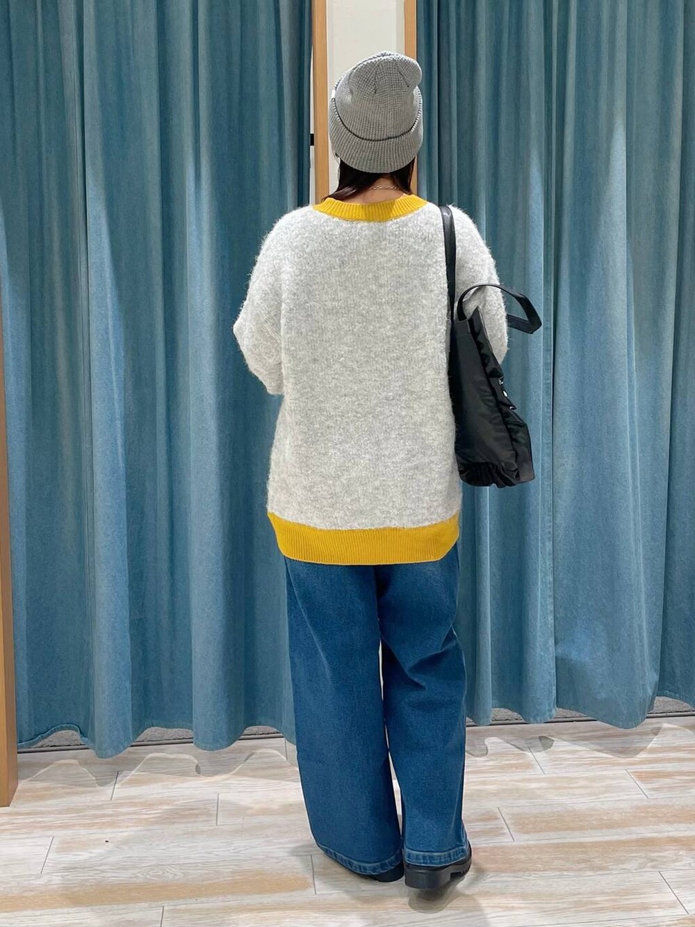 ブラック系のトートバッグ、ホワイト系のニット/セーター、ブルー系のデニムパンツを着用したレディースの冬コーディネートの3枚目の写真