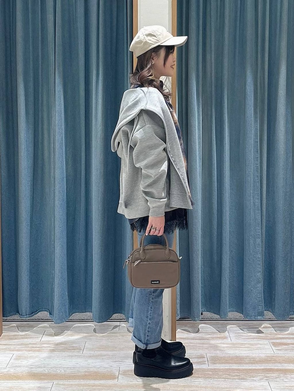 ブラック系のブーツ、ブラウン系のハンドバッグ、ブルー系のデニムパンツを着用したレディースの冬コーディネートの2枚目の写真