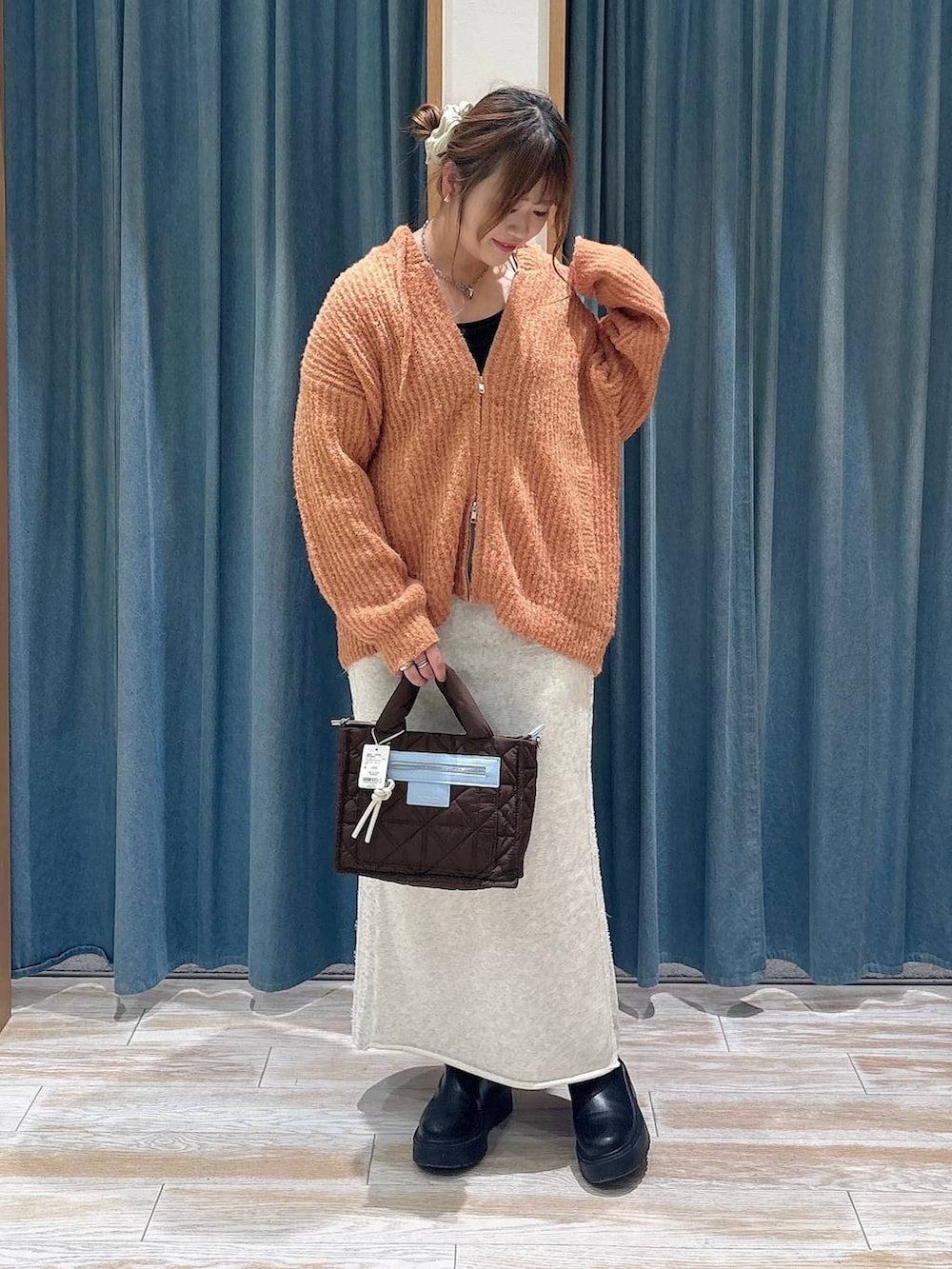 ベージュ系のスカート、オレンジ系のニット/セーター、ブラウン系のショルダーバッグを着用したレディースの秋コーディネートの4枚目の写真