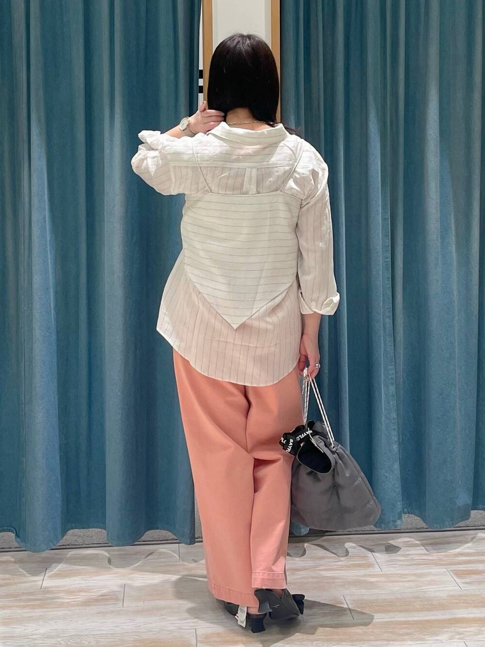 ブラック系のパンプス、グレー系のショルダーバッグ、ピンク系のデニムパンツを着用したレディースの冬コーディネートの3枚目の写真