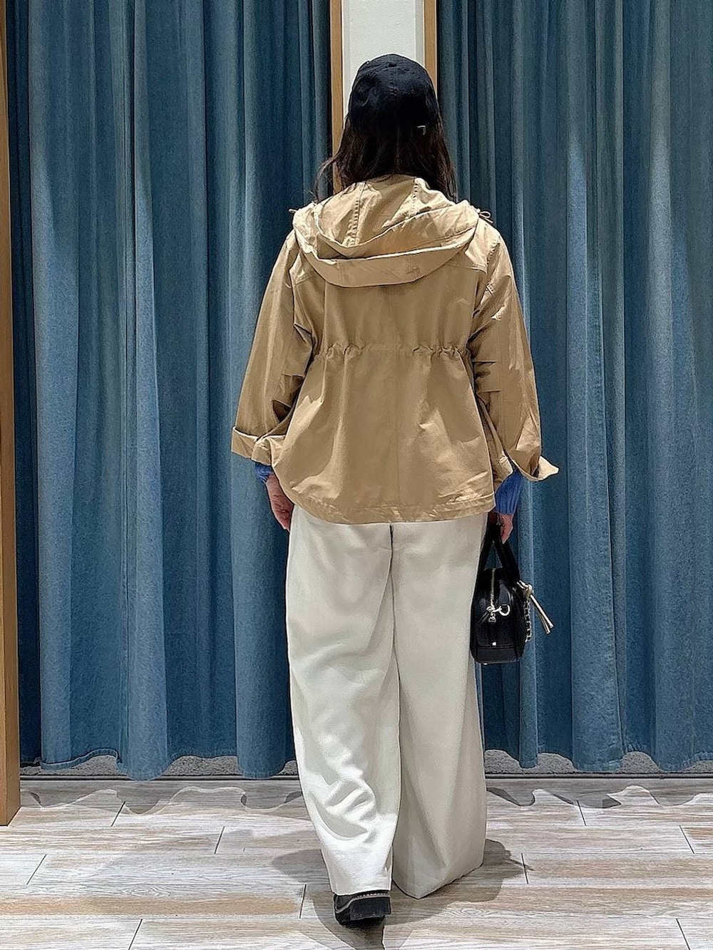 イエロー系のマウンテンパーカー、ブラック系のローファー、ブラック系のハンドバッグを着用したレディースの春コーディネートの3枚目の写真