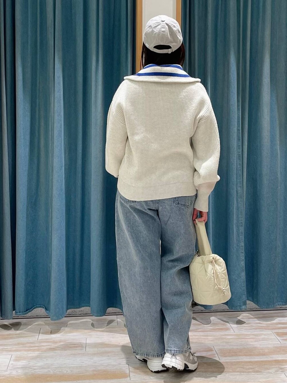 ブルー系のデニムパンツ、ベージュ系のショルダーバッグ、ホワイト系のスニーカーを着用したレディースの冬コーディネートの3枚目の写真