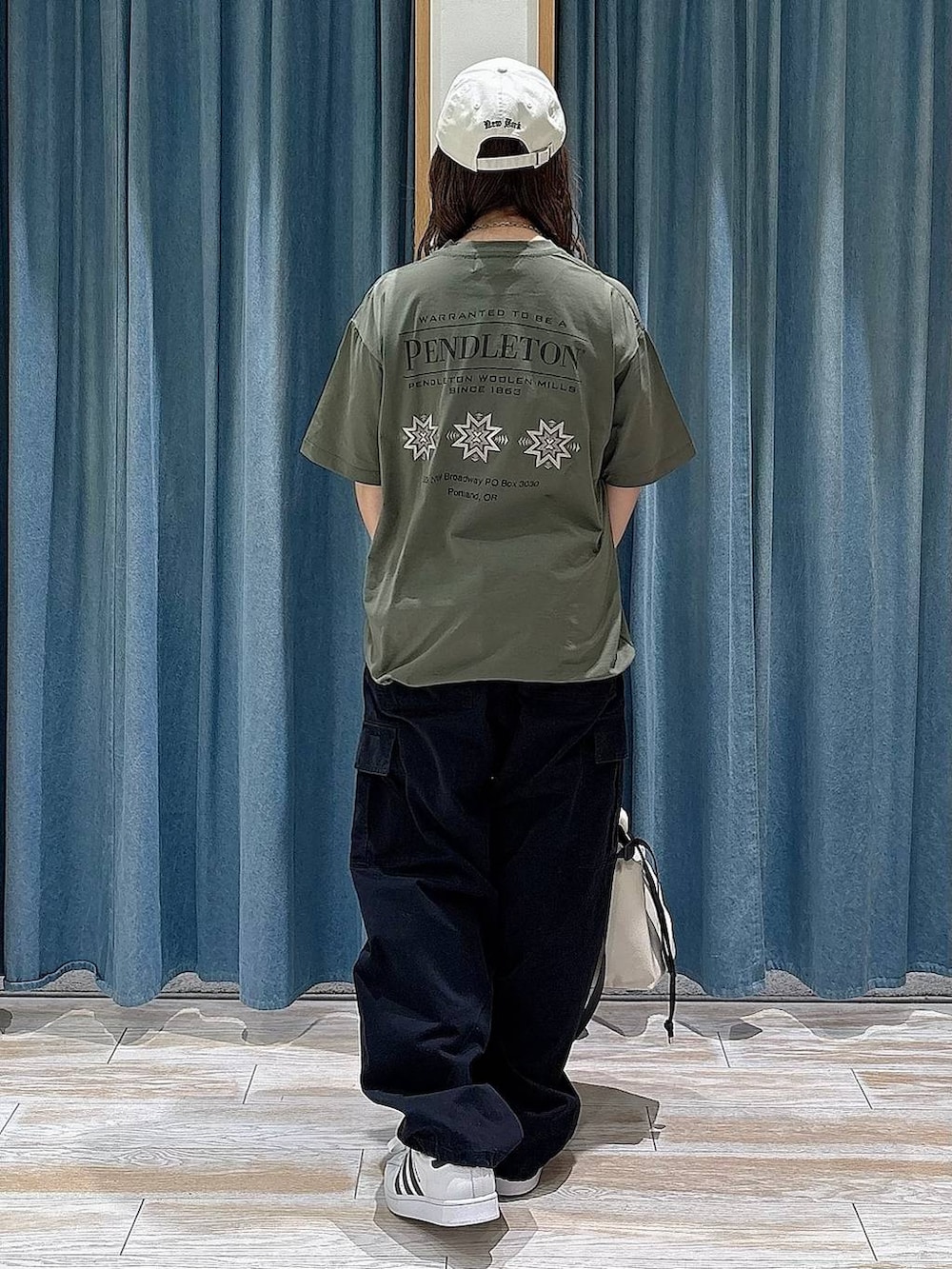 ホワイト系のトートバッグ、ホワイト系のスニーカー、ブラック系のカーゴパンツを着用したレディースの春コーディネートの3枚目の写真