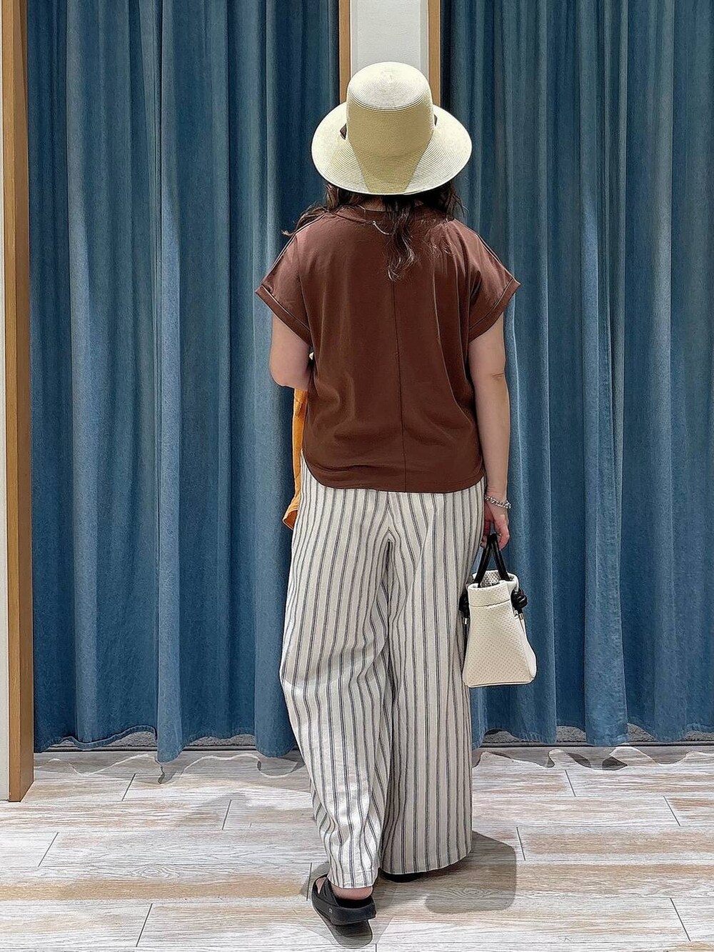 オレンジ系のシャツ/ブラウス、ホワイト系のその他パンツ、ベージュ系のショルダーバッグを着用したレディースの春コーディネートの3枚目の写真