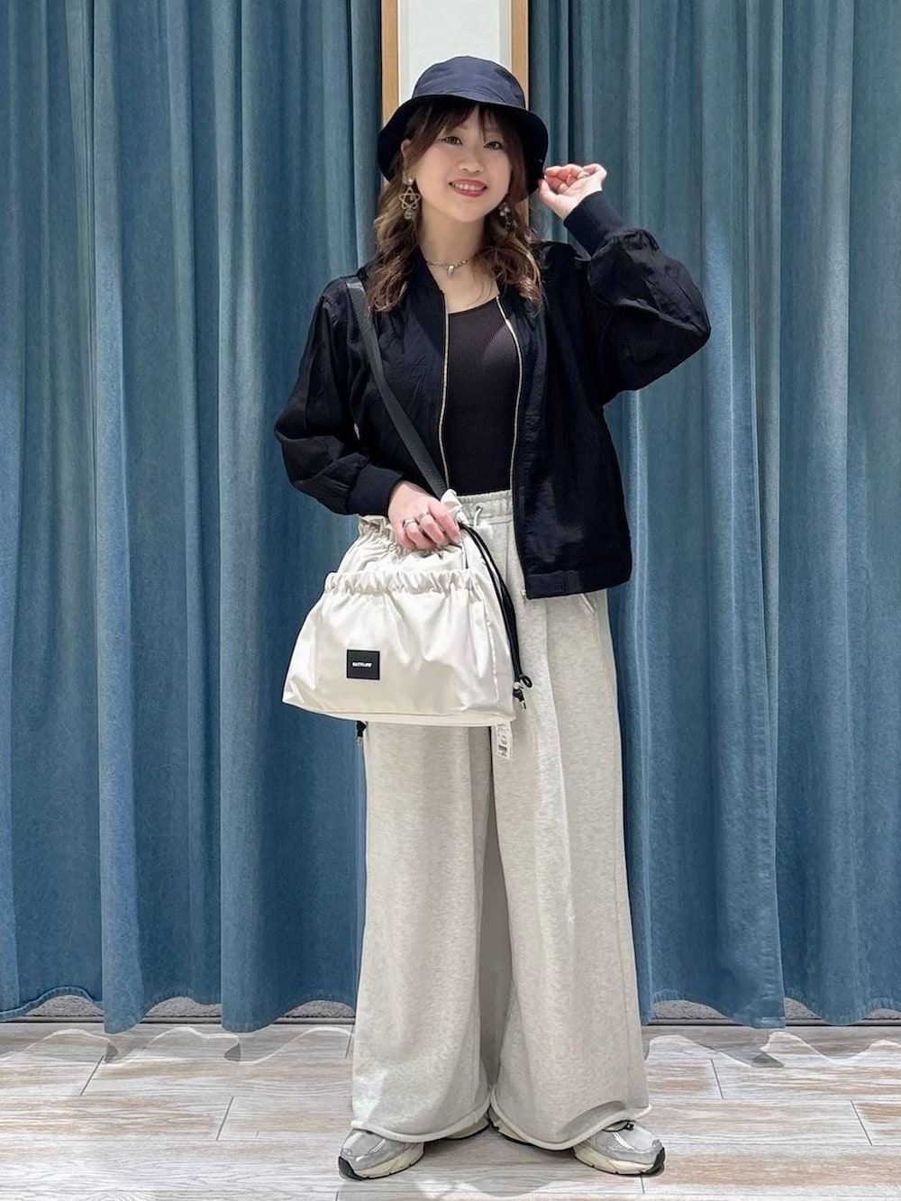 ホワイト系のトートバッグ、ブラック系のブルゾン、ホワイト系のスウェットパンツを着用したレディースの春コーディネートの4枚目の写真