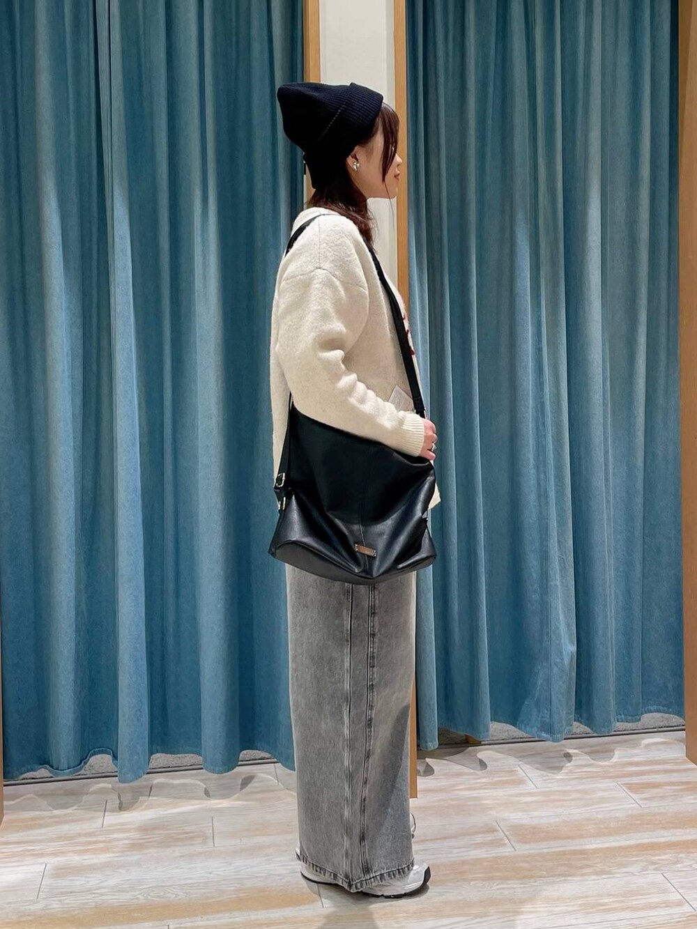 ブラック系のショルダーバッグ、ホワイト系のニット/セーター、グレー系のデニムパンツを着用したレディースの冬コーディネートの2枚目の写真