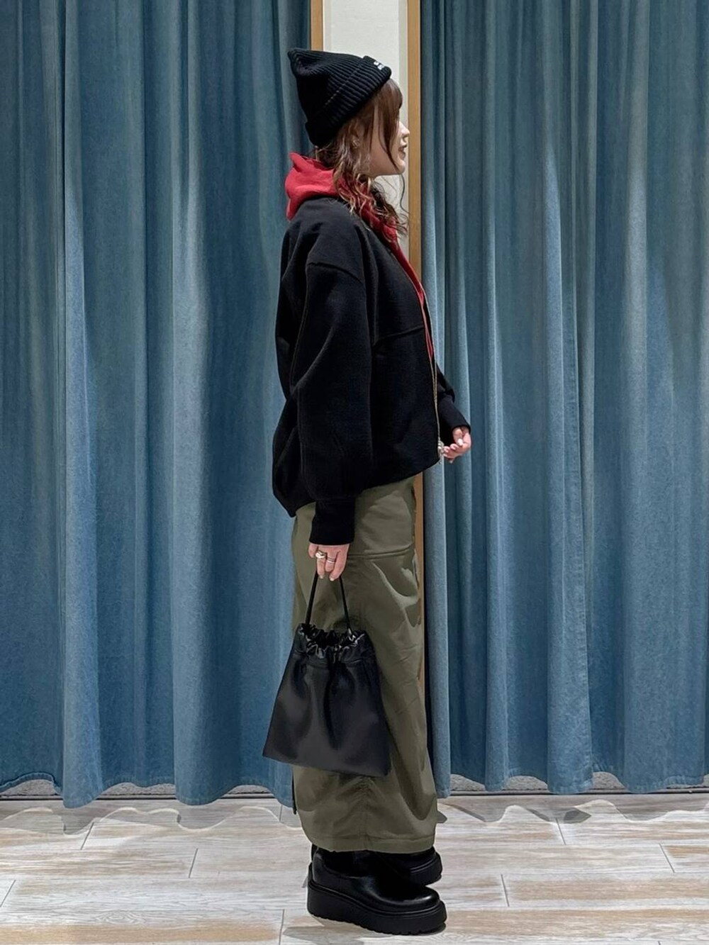 グリーン系のスカート、ブラック系のブルゾン、ブラック系のブーツを着用したレディースの秋コーディネートの3枚目の写真