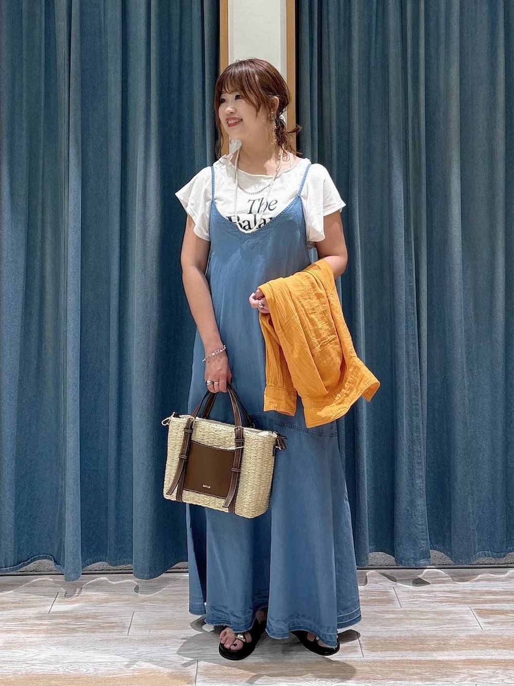 オレンジ系のシャツ/ブラウス、ブラウン系のショルダーバッグ、ブラック系のサンダルを着用したレディースの夏コーディネートの4枚目の写真