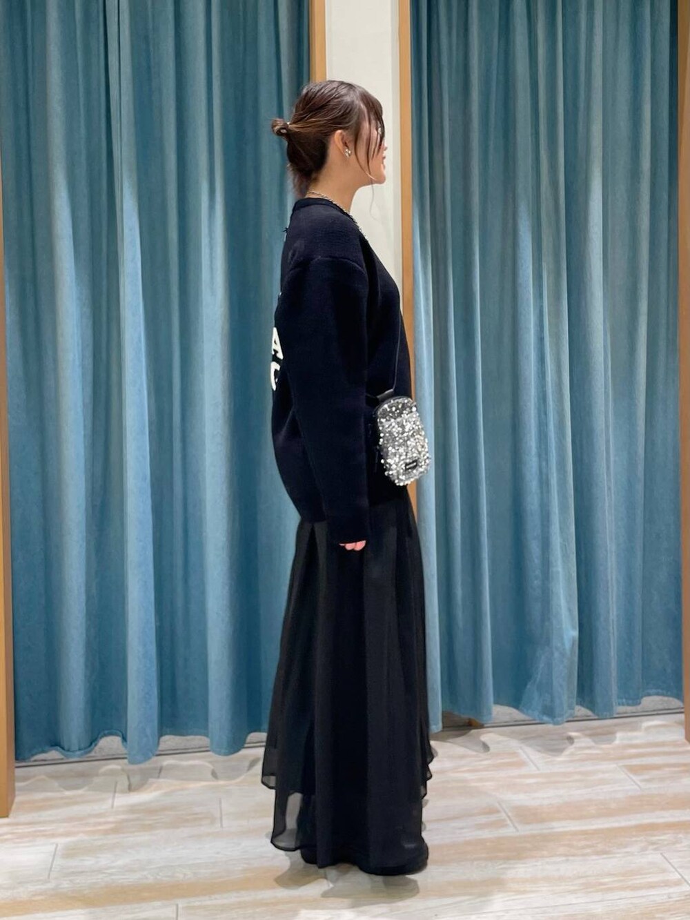 グレー系のショルダーバッグ、ブラック系のブーツ、ブラック系のニット/セーターを着用したレディースの冬コーディネートの3枚目の写真