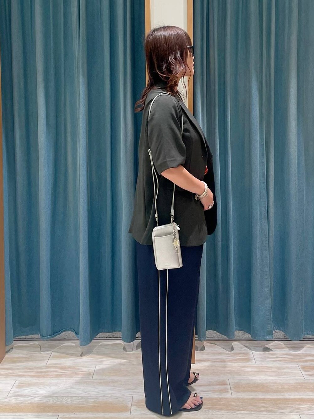 グレー系のテーラードジャケット、ブラック系のサンダル、ブルー系のその他パンツを着用したレディースの春コーディネートの2枚目の写真