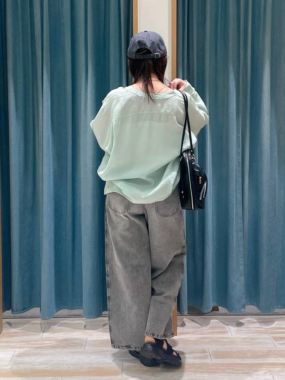 グレー系のデニムパンツ、グリーン系のシャツ/ブラウス、ブラック系のサンダルを着用したレディースの春コーディネートの3枚目の写真