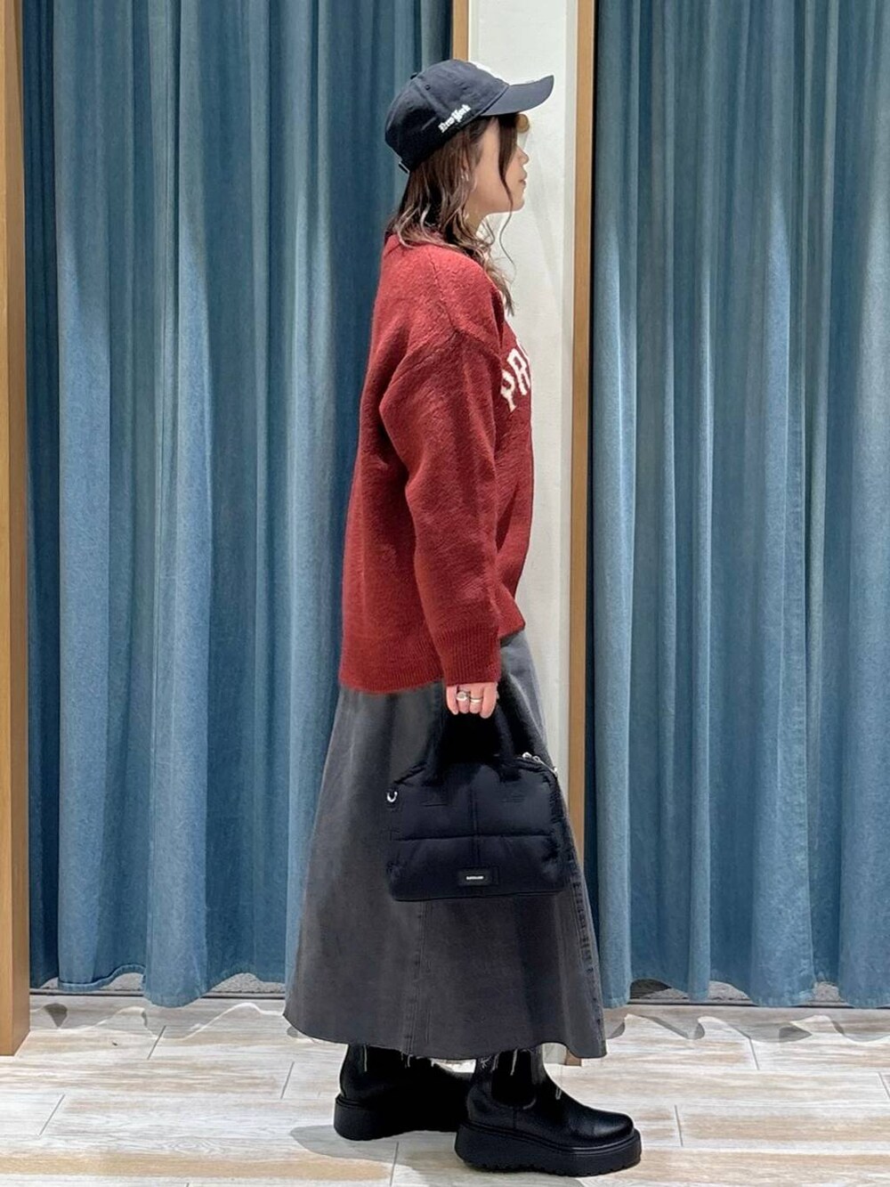 ブラック系のブーツ、ブラック系のスカート、ブラック系のボストンバッグを着用したレディースの秋コーディネートの2枚目の写真