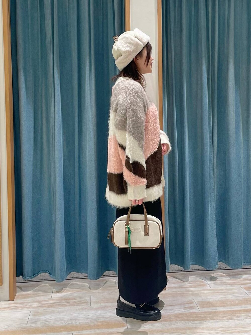 ホワイト系のカーディガン/ボレロ、その他のショルダーバッグ、ブラック系のスカートを着用したレディースの冬コーディネートの2枚目の写真