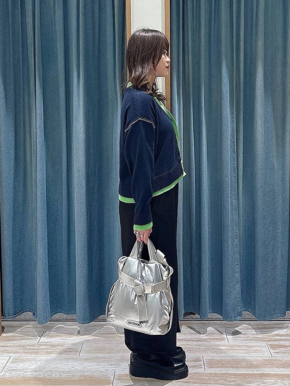 シルバー系のトートバッグ、ブラック系のブーツ、ブラック系のスカートを着用したレディースの冬コーディネートの2枚目の写真