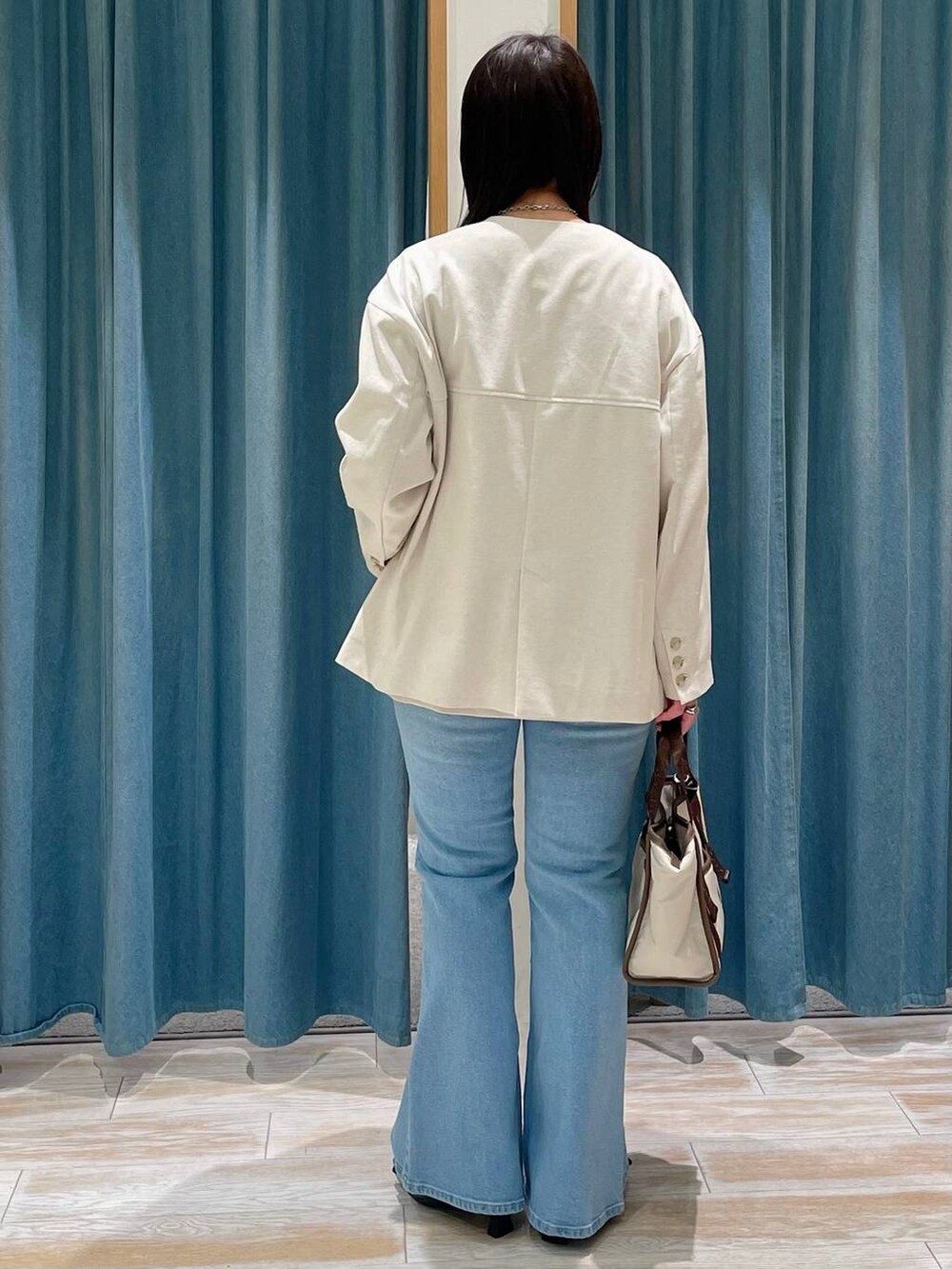 ブラック系のパンプス、イエロー系のTシャツ/カットソー、ブルー系のデニムパンツを着用したレディースの春コーディネートの3枚目の写真