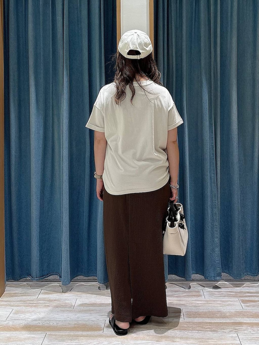 ホワイト系のTシャツ/カットソー、ブラック系のサンダル、ベージュ系のショルダーバッグを着用したレディースの夏コーディネートの3枚目の写真