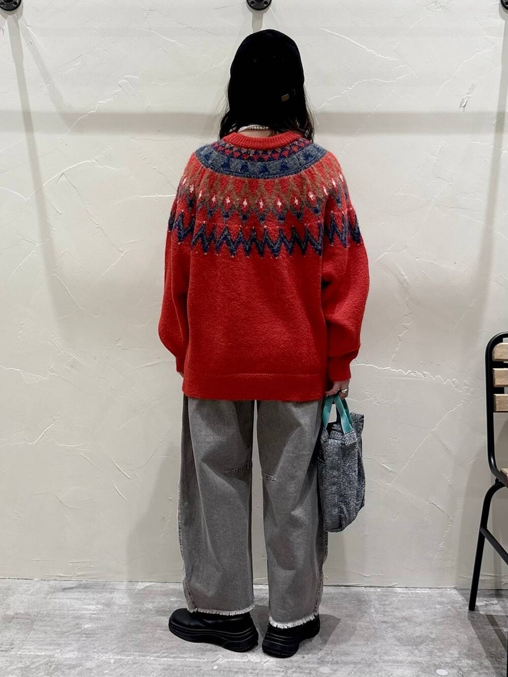 グレー系のデニムパンツ、シルバー系のトートバッグ、レッド系のニット/セーターを着用したレディースの冬コーディネートの3枚目の写真