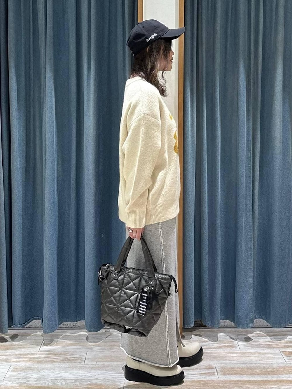 ベージュ系のブーツ、ホワイト系のニット/セーター、グレー系のスカートを着用したレディースの冬コーディネートの2枚目の写真