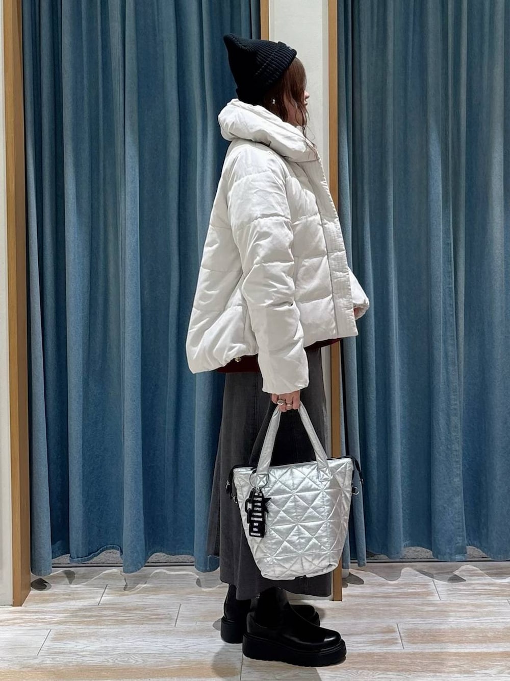 ベージュ系のダウンジャケット/コート、ブラック系のブーツ、ブラック系のスカートを着用したレディースの秋コーディネートの2枚目の写真