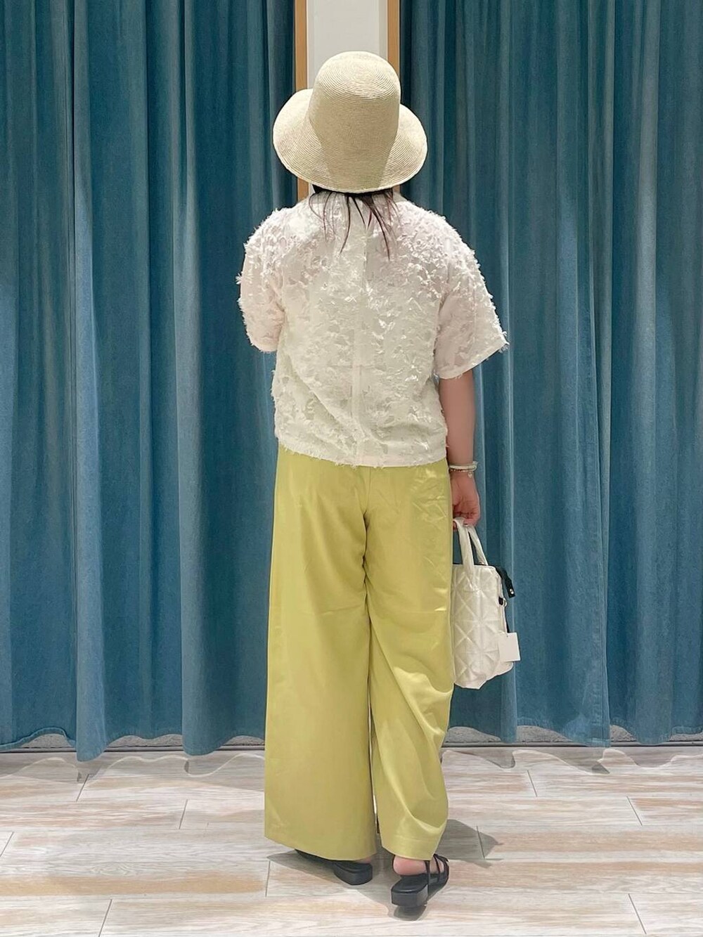 イエロー系のその他パンツ、ホワイト系のハンドバッグ、ブラック系のサンダルを着用したレディースの春コーディネートの2枚目の写真