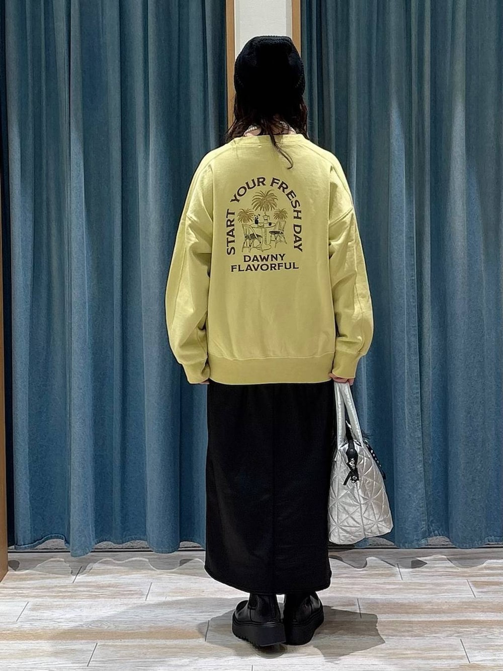 ブラック系のブーツ、イエロー系のスウェット、ブラック系のスカートを着用したレディースの冬コーディネートの3枚目の写真