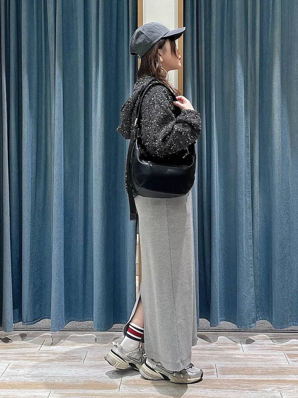 ブラック系のショルダーバッグ、ブラック系のブルゾン、グレー系のワンピースを着用したレディースの春コーディネートの2枚目の写真