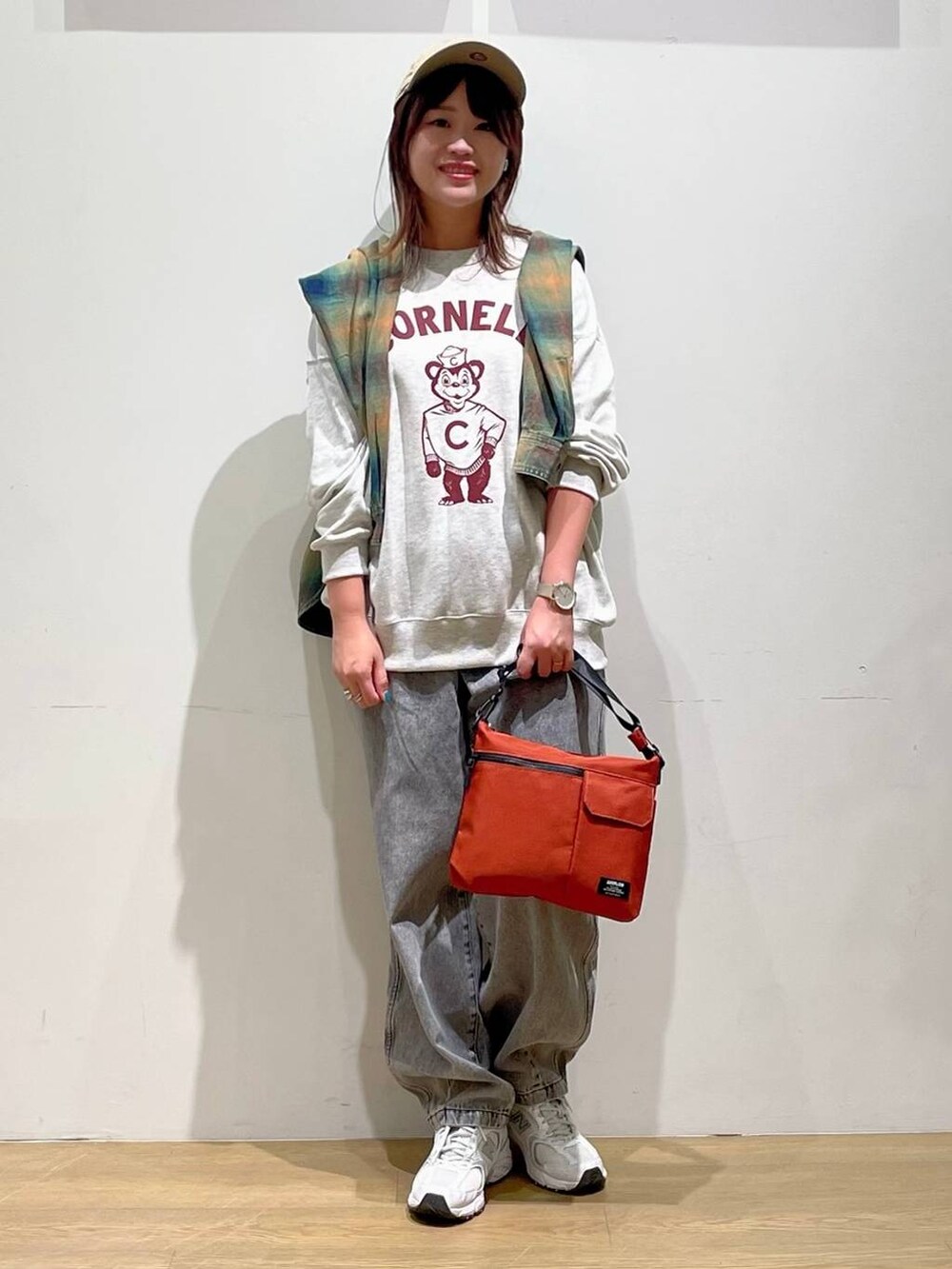 オレンジ系のシャツ/ブラウス、ブラック系のデニムパンツ、オレンジ系のショルダーバッグを着用したレディースの秋コーディネートの2枚目の写真