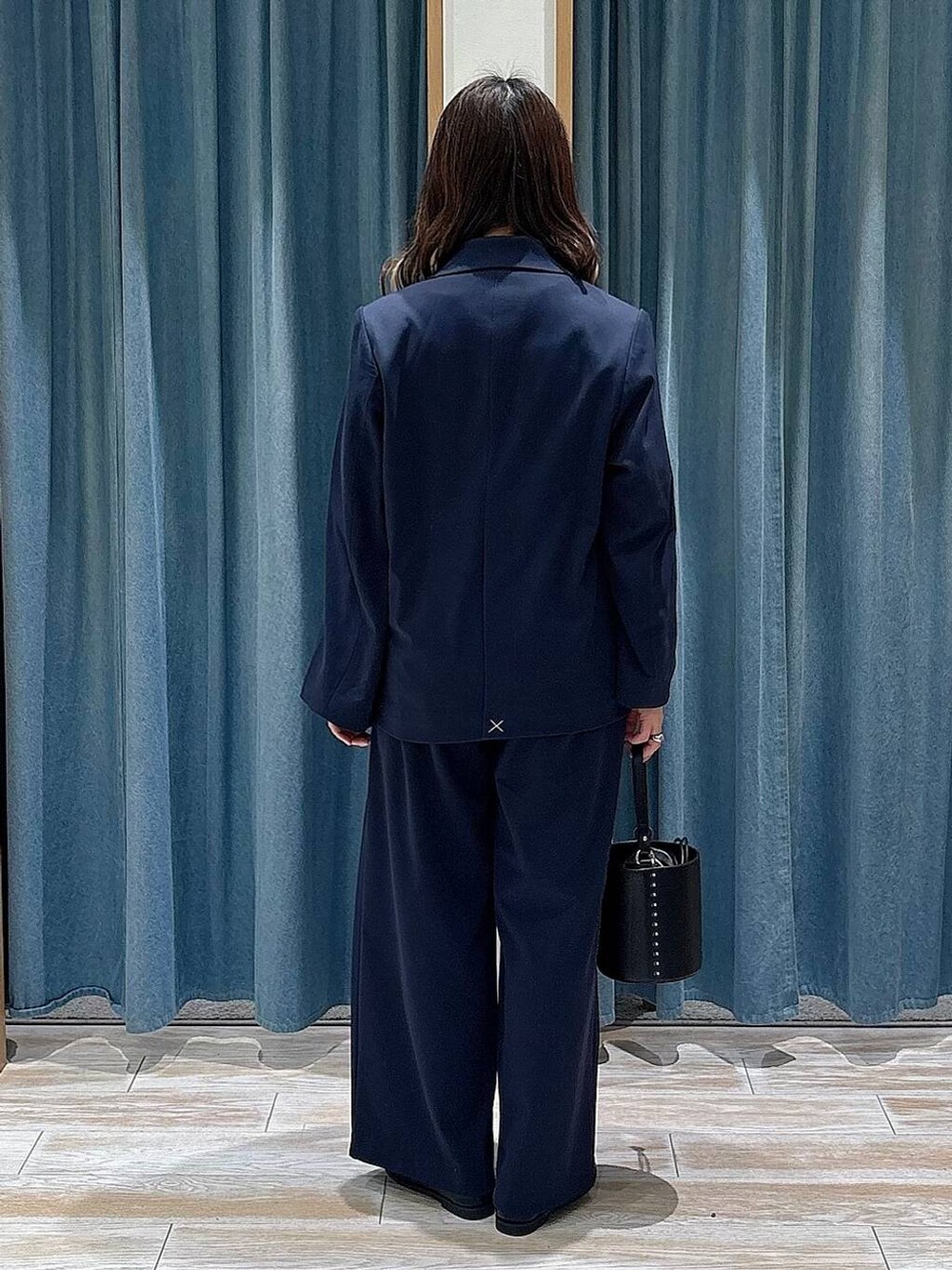 ブラック系のハンドバッグ、ブルー系のテーラードジャケット、ブルー系のスラックスを着用したレディースの冬コーディネートの3枚目の写真