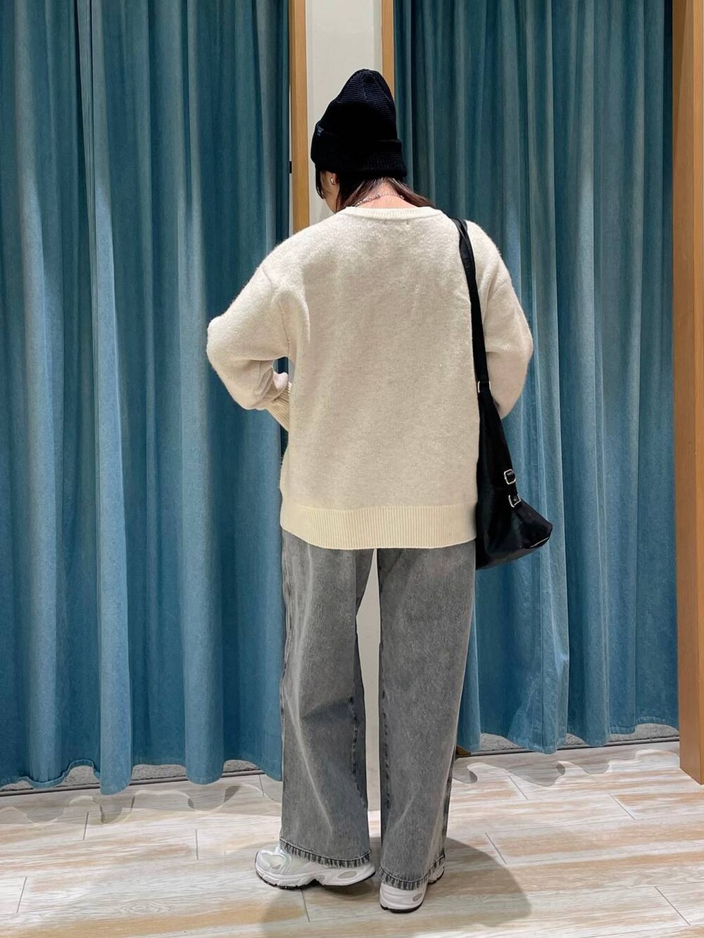 ブラック系のショルダーバッグ、ホワイト系のニット/セーター、グレー系のデニムパンツを着用したレディースの冬コーディネートの3枚目の写真